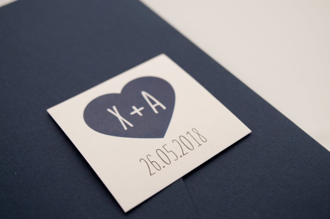 Προσκλητήριο Γάμου: Λεπτομέρεια Pocket folder γραμμωτό ναυτικό μπλε και Καρτάκι γραμμωτό υπόλευκο με εκτύπωση μελάνι ναυτικό μπλε μονογράμματα_Κωδικός 5917