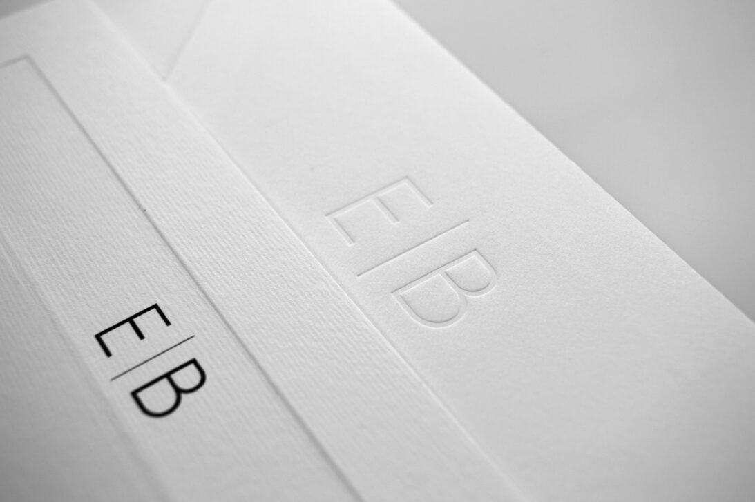 Προσκλητήριο Γάμου: Λεπτομέρεια μονογράμματα βαθυτυπία (letterpress) χωρίς χρώμα σε Φάκελο γραμμωτό υπόλευκο και γκοφρέ πλαίσιο σε γραμμωτή υπόλευκη Κάρτα με εκτύπωση μελάνι μαύρο_Κωδικός 5955