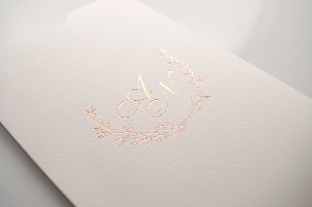 Προσκλητήριο Γάμου: Λεπτομέρεια Φάκελος μπιμπικωτός λευκός με θερμοτυπία ροζ χρυσό και θέμα κλαδιά / στεφάνι και μονογράμματα_Κωδικός 6129
