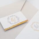 Λεπτομέρεια Προσκλητήριου Γάμου: Φάκελος διάστασης 13,3x18,3 εκατ. σε χαρτί γκοφρέ γραμμωτό (ανάγλυφο) γκρι 160 γραμ., καρτάκι 4x6,5 εκατ. με θέμα στεφανάκι, μονογράμματα και φάσα από φύλλο χρυσού και Κάρτα σε χαρτί γκοφρέ γραμμωτό (ανάγλυφο) υπόλευκο 250γραμ. με εκτύπωση μελάνι και θέμα στεφανάκι, μονογράμματα και φάσα από φύλλο χρυσού_Κωδικός 6153