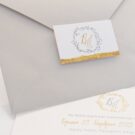 Λεπτομέρεια Προσκλητήριου Γάμου: Φάκελος διάστασης 13,3x18,3 εκατ. σε χαρτί γκοφρέ γραμμωτό (ανάγλυφο) γκρι 160 γραμ., καρτάκι 4x6,5 εκατ. με θέμα στεφανάκι, μονογράμματα και φάσα από φύλλο χρυσού και Κάρτα σε χαρτί γκοφρέ γραμμωτό (ανάγλυφο) υπόλευκο 250γραμ. με εκτύπωση μελάνι και θέμα στεφανάκι, μονογράμματα και φάσα από φύλλο χρυσού_Κωδικός 6153