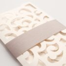 Λεπτομέρεια Φάκελος τρίπτυχος τρυπητός Lasercut 12,2 x 21,5 εκατ. μεταλλιζέ υπόλευκος και Κάρτα μεταλλιζέ υπόλευκη με φάσα λαμιναριστή λιλά 3,5x13 εκατ.