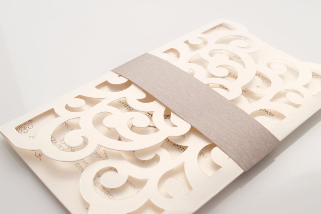 Λεπτομέρεια Φάκελος τρίπτυχος τρυπητός Lasercut 12,2 x 21,5 εκατ. μεταλλιζέ υπόλευκος και Κάρτα μεταλλιζέ υπόλευκη με φάσα λαμιναριστή λιλά 3,5x13 εκατ.