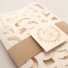 Λεπτομέρεια Φάκελος τρίπτυχος τρυπητός Lasercut 12,2 x 21,5 εκατ. μεταλλιζέ υπόλευκος και Κάρτα μεταλλιζέ υπόλευκη με φάσα λαμιναριστή χρυσή 3,5x13 εκατ. και καρτάκι 5x5 εκατ.