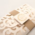 Λεπτομέρεια Φάκελος τρίπτυχος τρυπητός Lasercut 12,2 x 21,5 εκατ. μεταλλιζέ υπόλευκος και Κάρτα μεταλλιζέ υπόλευκη με φάσα λαμιναριστή χρυσή 3,5x13 εκατ. και καρτάκι 5x5 εκατ.