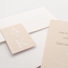 Λεπτομέρεια Προσκλητηρίου Γάμου: Φάκελος διάστασης 12,7x18,8 εκατ. σε χαρτί γκοφρέ (ανάγλυφο) μπιμπικωτό λευκό 170 γραμ., καρτάκι 6x4 εκατ. με μονογράμματα ζευγαριού και Κάρτα σε χαρτί γκοφρέ (ανάγλυφο) μπιμπικωτό λευκό 250 γραμ. με εκτύπωση μελάνι και θέμα μονογράμματα σε χρώμα άμμου_Κωδικός 6144