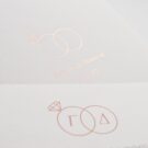 Λεπτομέρεια Προσκλητηρίου Γάμου: Φάκελος τραβηχτός διάστασης 14,5x20,5 εκατ. γκοφρέ (ανάγλυφο) μπιμπικωτό λευκό 250γραμ. και μονογράμματα σε θερμοτυπία ροζ χρυσό με θέμα βέρες, ονόματα ζευγαριού και ημερομηνία και Κάρτα σε χαρτί (ανάγλυφο) μπιμπικωτό λευκό 250 γραμ. με εκτύπωση μελάνι γκρι και ροζ χρυσό και θέμα βέρες, μονογράμματα και ημερομηνία _Κωδικός 0017