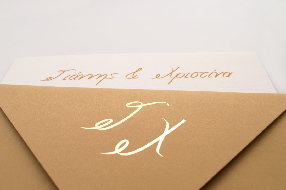 Λεπτομέρεια Προσκλητηρίου Γάμου: Φάκελος διάστασης 16x22 εκατ. σε χαρτί κραφτ (καφέ άμμου) 160γραμ. με μονογράμματα σε χρυσοτυπία γυαλιστερή και Κάρτα σε χαρτί γκοφρέ (ανάγλυφο) γραμμωτό υπόλευκο 250 γραμ. με εκτύπωση μελάνι χρυσό και μαύρο_Κωδικός ΓΕΠ 0029