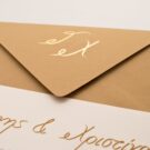 Λεπτομέρεια Προσκλητηρίου Γάμου: Φάκελος διάστασης 16x22 εκατ. σε χαρτί κραφτ (καφέ άμμου) 160γραμ. με μονογράμματα σε χρυσοτυπία γυαλιστερή και Κάρτα σε χαρτί γκοφρέ (ανάγλυφο) γραμμωτό υπόλευκο 250 γραμ. με εκτύπωση μελάνι χρυσό και μαύρο_Κωδικός ΓΕΠ 0029