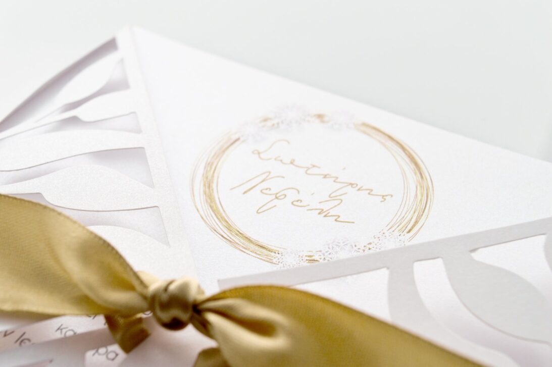 Λεπτομέρεια Προσκλητηρίου Γάμου: Φάκελος τρυπητός Lasercut 16,4x16,4 εκατ. σε χαρτί λείο μεταλλιζέ (περλέ) 250 γραμ., κορδέλα σατέν χρυσή 2,5 εκατ. και Κάρτα σε χαρτί λείο μεταλλιζέ (περλέ) 250 γραμ. με εκτύπωση μελάνι γκρι και χρυσό και θέμα νιφάδες, Χριστούγεννα_Κωδικός ΓΝΣ3085