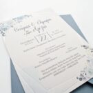 Λεπτομέρεια Προσκλητηρίου Γάμου και Βάπτισης: Φάκελος διάστασης 16x22 εκατ. σε χαρτί οικολογικό (άγρα υφή) βρώμικο γαλάζιο 160 γραμ., και Κάρτα σε χαρτί γκοφρέ (μπιμπικωτό) λευκό 250 γραμ. με εκτύπωση μελάνι και θέμα λουλούδια και γεωμετρικό πλαίσιο ασημοτυπία_Κωδικός ΓΒΝΣ 2014