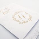 Λεπτομέρεια Προσκλητηρίου Γάμου: Κάρτα διάστασης 21x15εκατ. σε χαρτί γκοφρέ μπιμπικωτό λευκό 250 γραμ. με εκτύπωση μελάνι γκρι και χρυσό και Φάσα 11,4x15,2 εκατ. σε χαρτί γκοφρέ μπιμπικωτό 250 γραμ. με εκτύπωση μελάνι με θέμα στεφάνι και μονογράμματα_Κωδικός ΓΝΣ3010