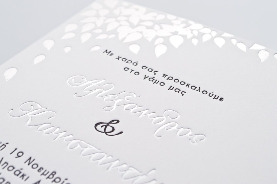 Λεπτομέρεια Προσκλητηρίου Γάμου: Κάρτα σε χαρτί βαμβακερό λευκό 1000 γραμ. με εκτύπωση κειμένου σε βαθυτυπία (letterpress) σε χρώμα μαύρο (μαυροτυπία) και ασημί (ασημοτυπία) και φύλλα σε βαθυτυπία ασημοτυπία_Κωδικός ΓΝΣ 3033