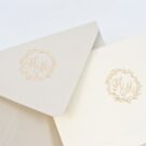 Λεπτομέρεια Σετ φακέλου διάστασης 9,5x13 σε χαρτί γκοφρέ γραμμωτό γκρι με εκτύπωση στεφανάκι και μονογράμματα σε χρυσοτυπίσ και Οικογενειακής κάρτας (family card) δίπτυχη διάστασης 9x12,5 με γκοφρέ πλαίσιο σε χαρτί γκρογέ γραμμωτό ιβουάρ 250 γραμ. και εκτύπωση δύο όψεων: α' όψη στεφανάκι και μονογράμματα σε χρυσοτυπία και β' όψη εκτύπωση ονομάτων και διεύθυνσης με μελάνι γκρι